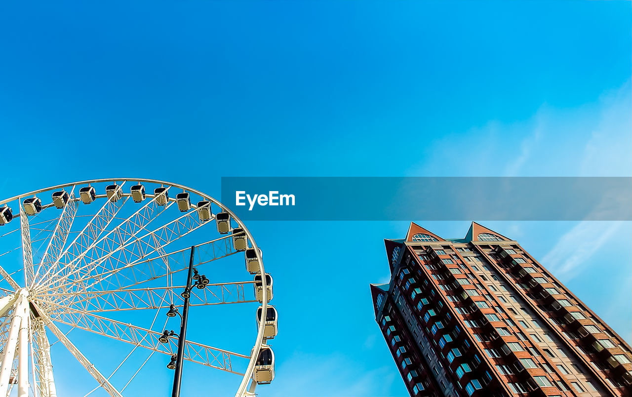 LOW ANGLE VIEW OF FERRIS WHEEL AGAINST BUILDINGS IN CITY