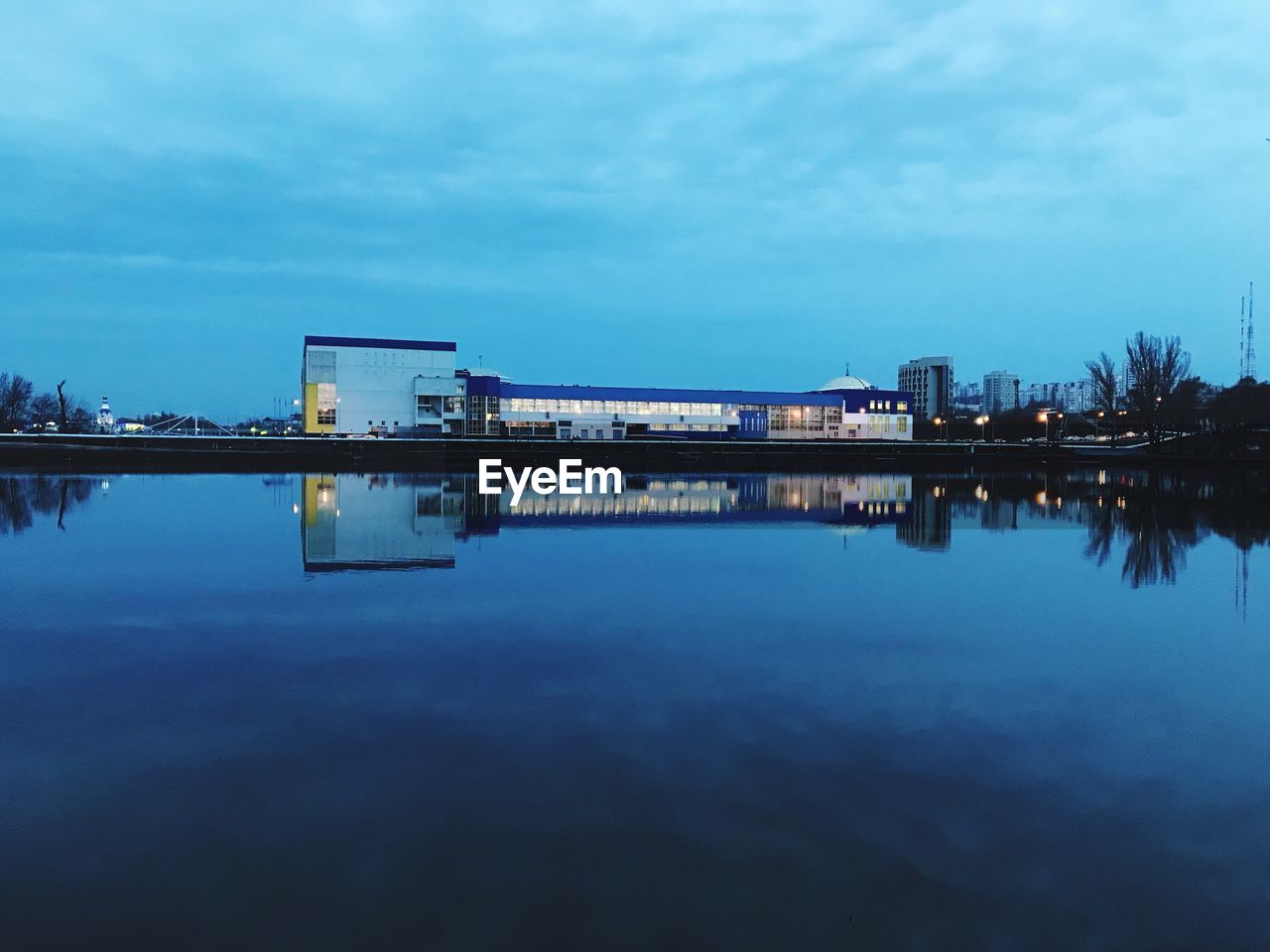 REFLECTION OF BUILDING IN LAKE AGAINST SKY