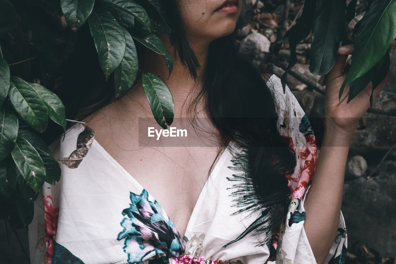 Mid section of a woman in floral dress against tropical leaves