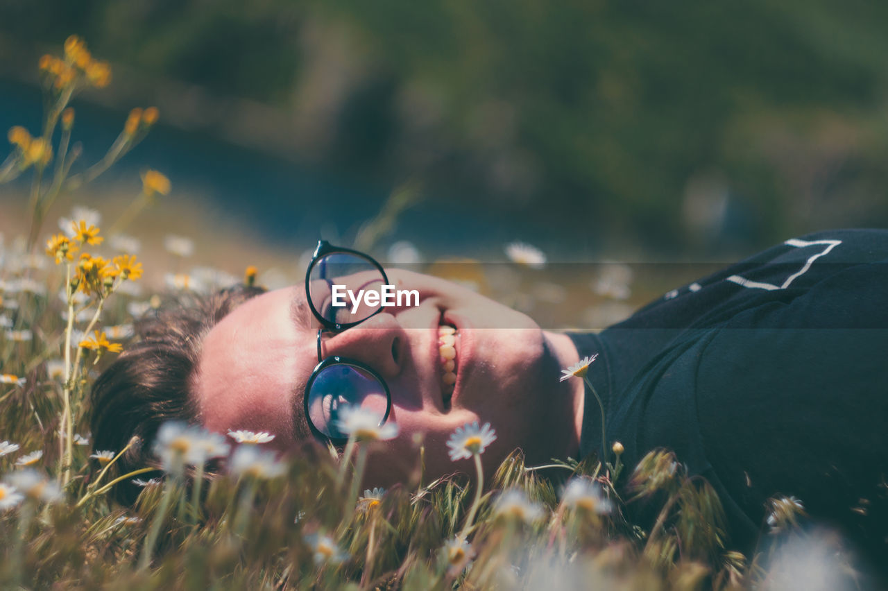  young man wearing eyeglasses while lying on meadow