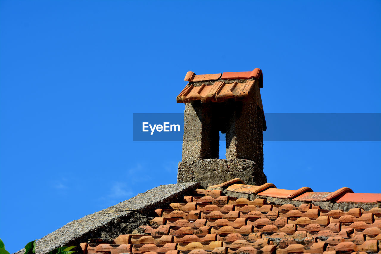 Low angle view of old roof against clear blue sky