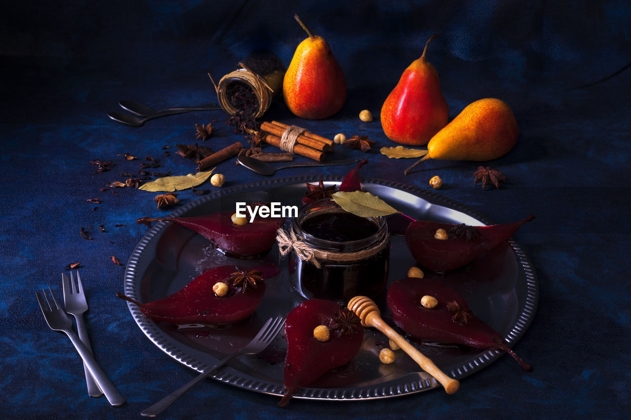 High angle view of hibiscus poached pears, sweet fruit dessert on dark blue table background.