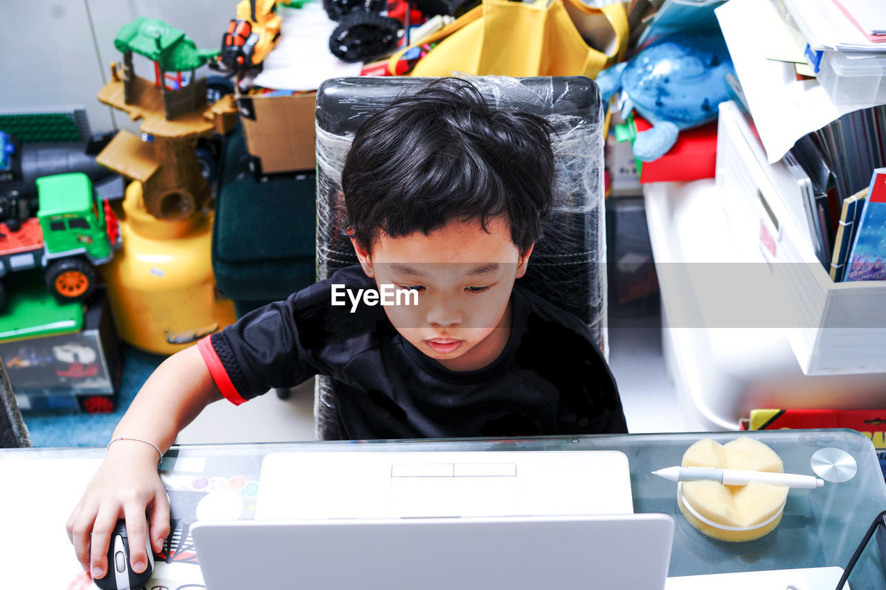 Boy learning over laptop while sitting on table at home