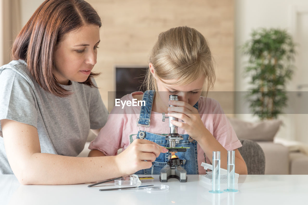 Mother helping daughter in science project at home