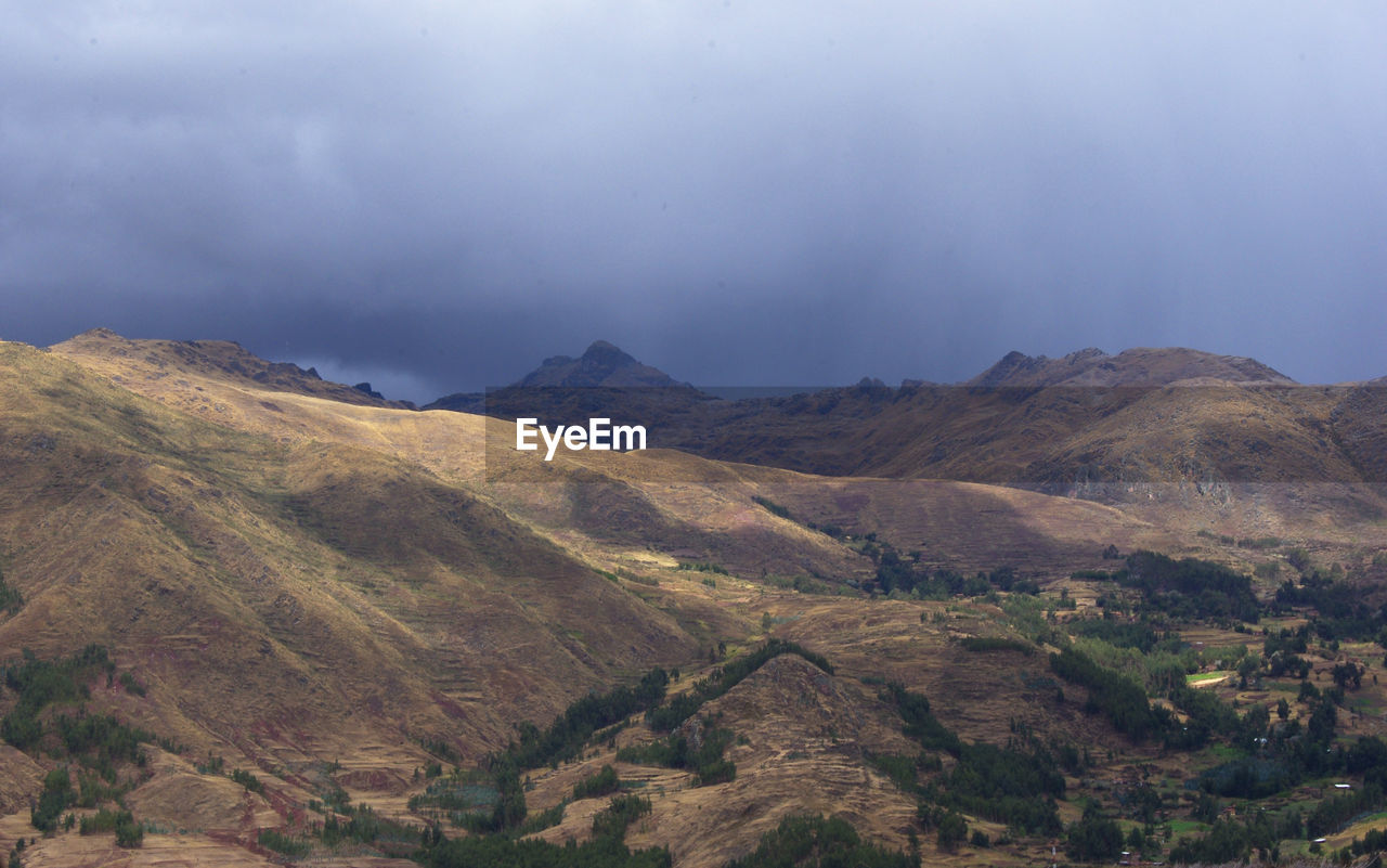 Scenic view of mountains against sky with dark clouds