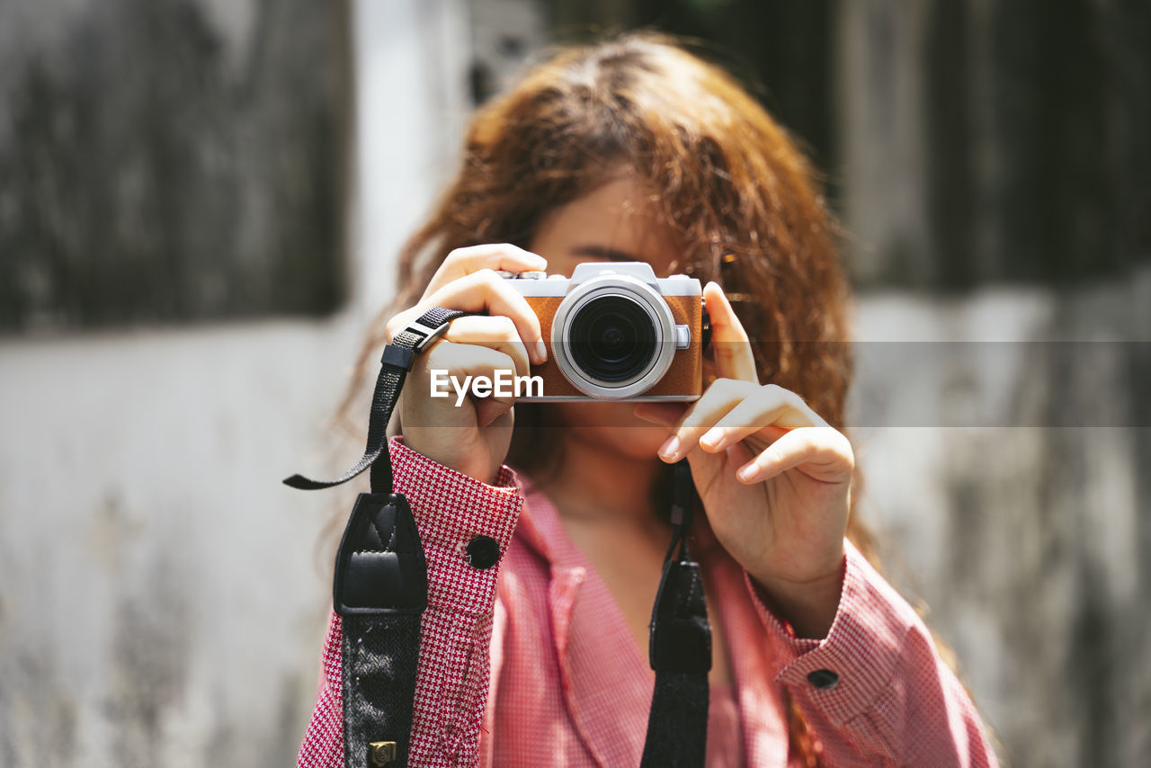 Portrait of woman photographing while standing outdoors