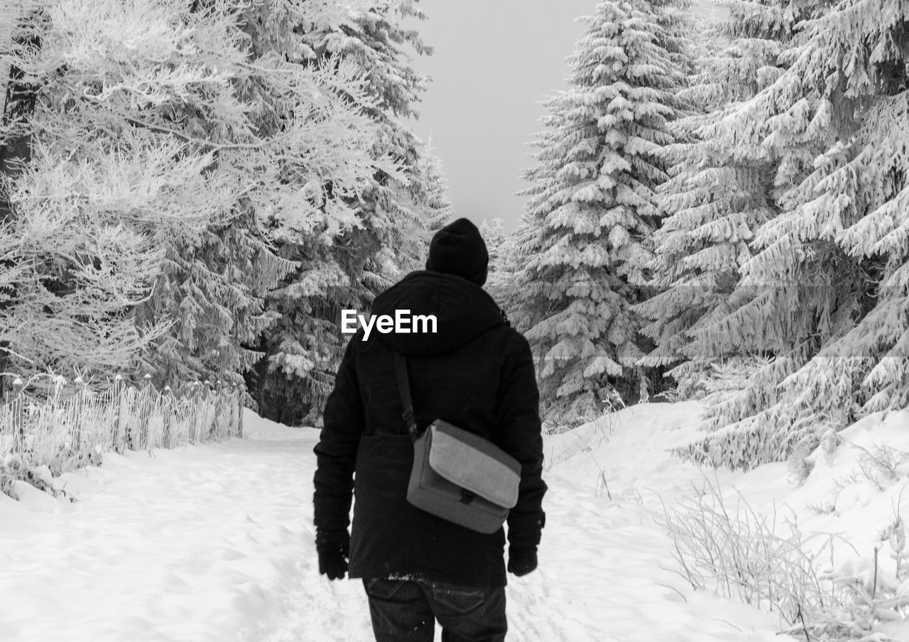 REAR VIEW OF MAN ON SNOW COVERED LANDSCAPE