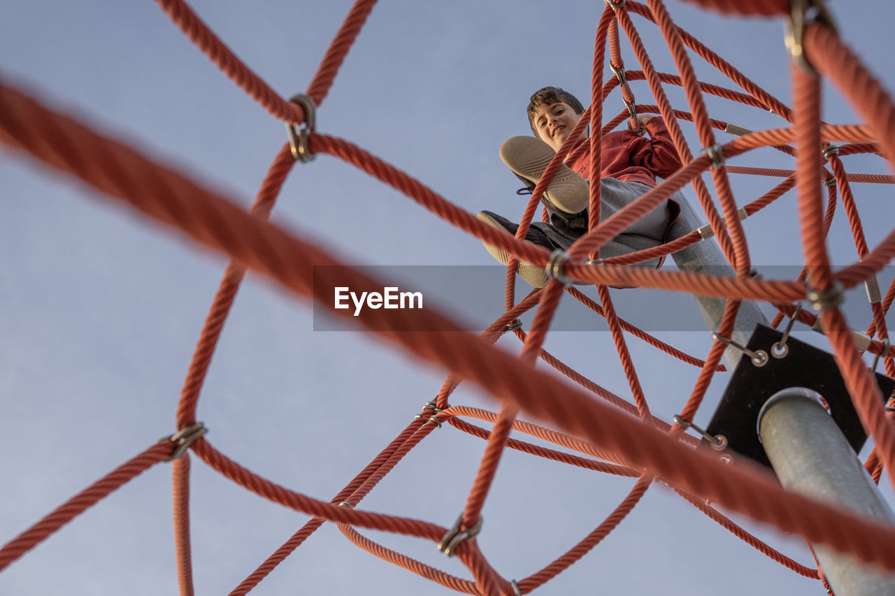 Kid on the top looking down after climbing the ropes in a playground