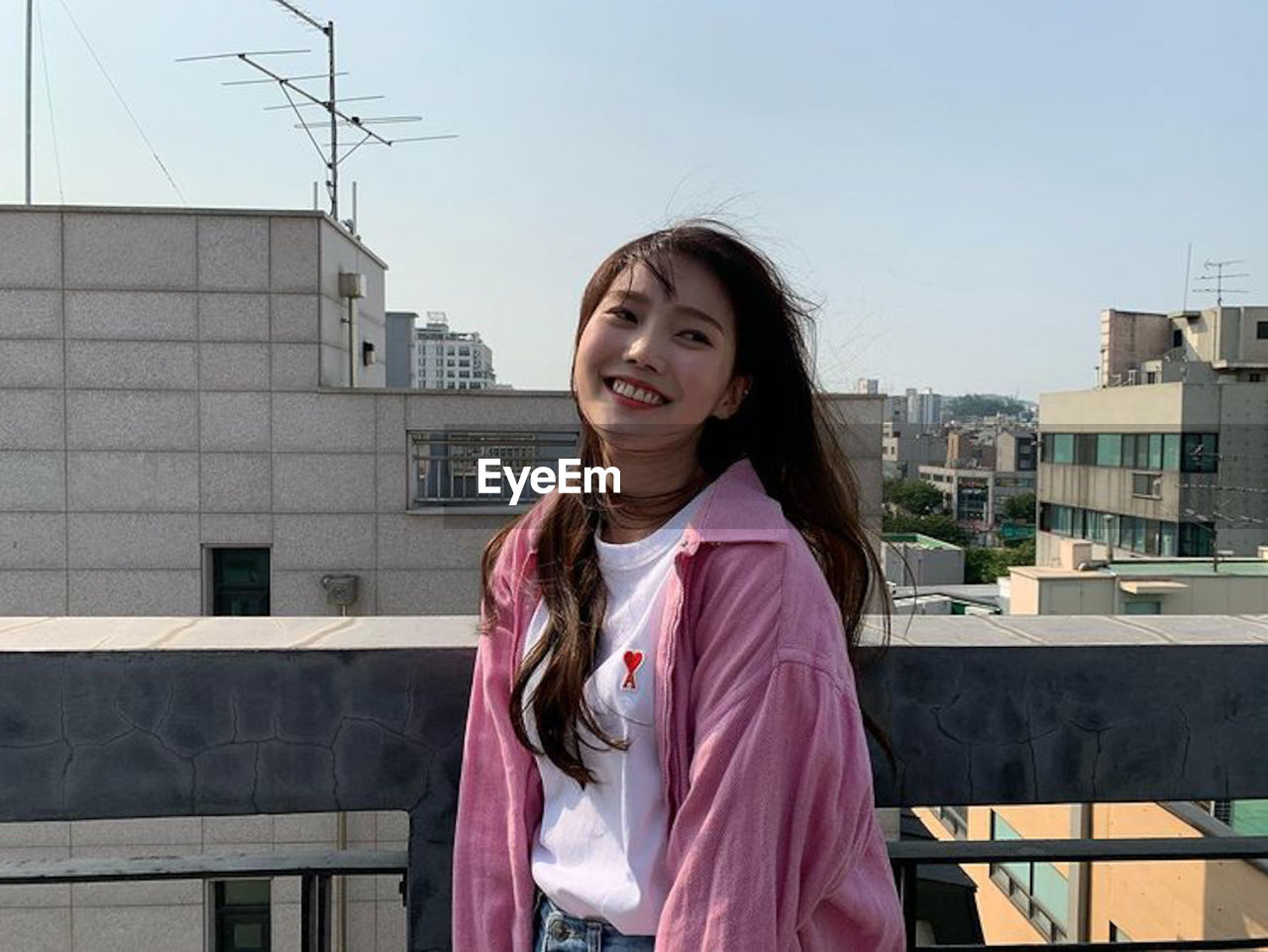 PORTRAIT OF SMILING WOMAN STANDING AGAINST BUILDING IN CITY