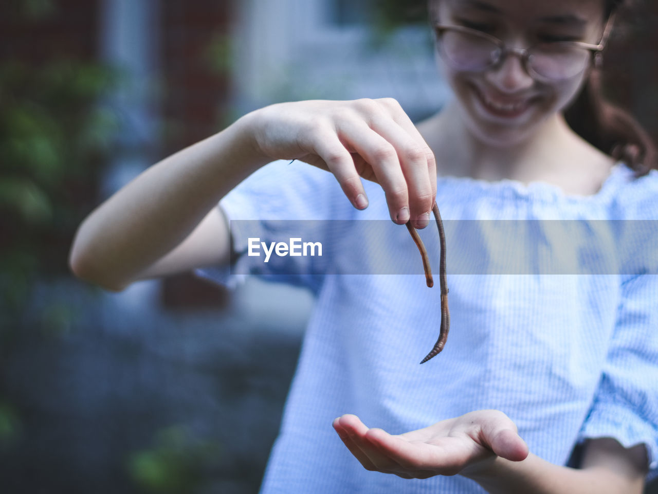 The girl holds an earthworm in her hands.