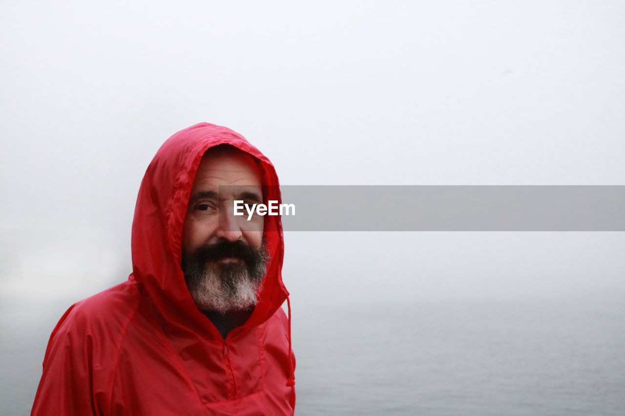 Portrait of man in red jacket against sea