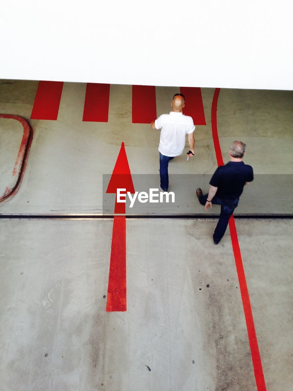 High angle view of men walking by arrow symbol at subway station