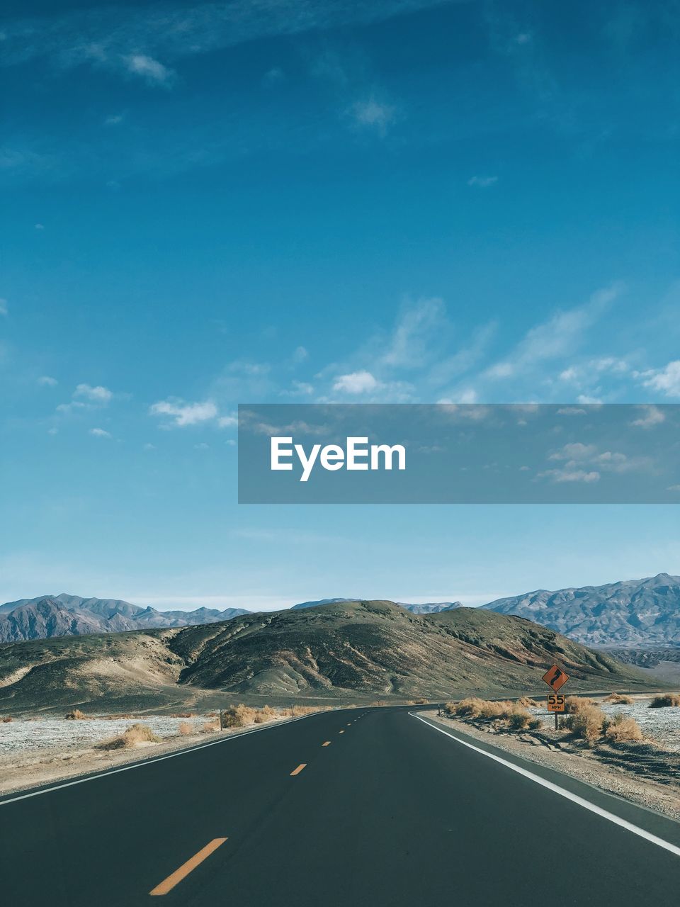 Road by mountains against blue sky