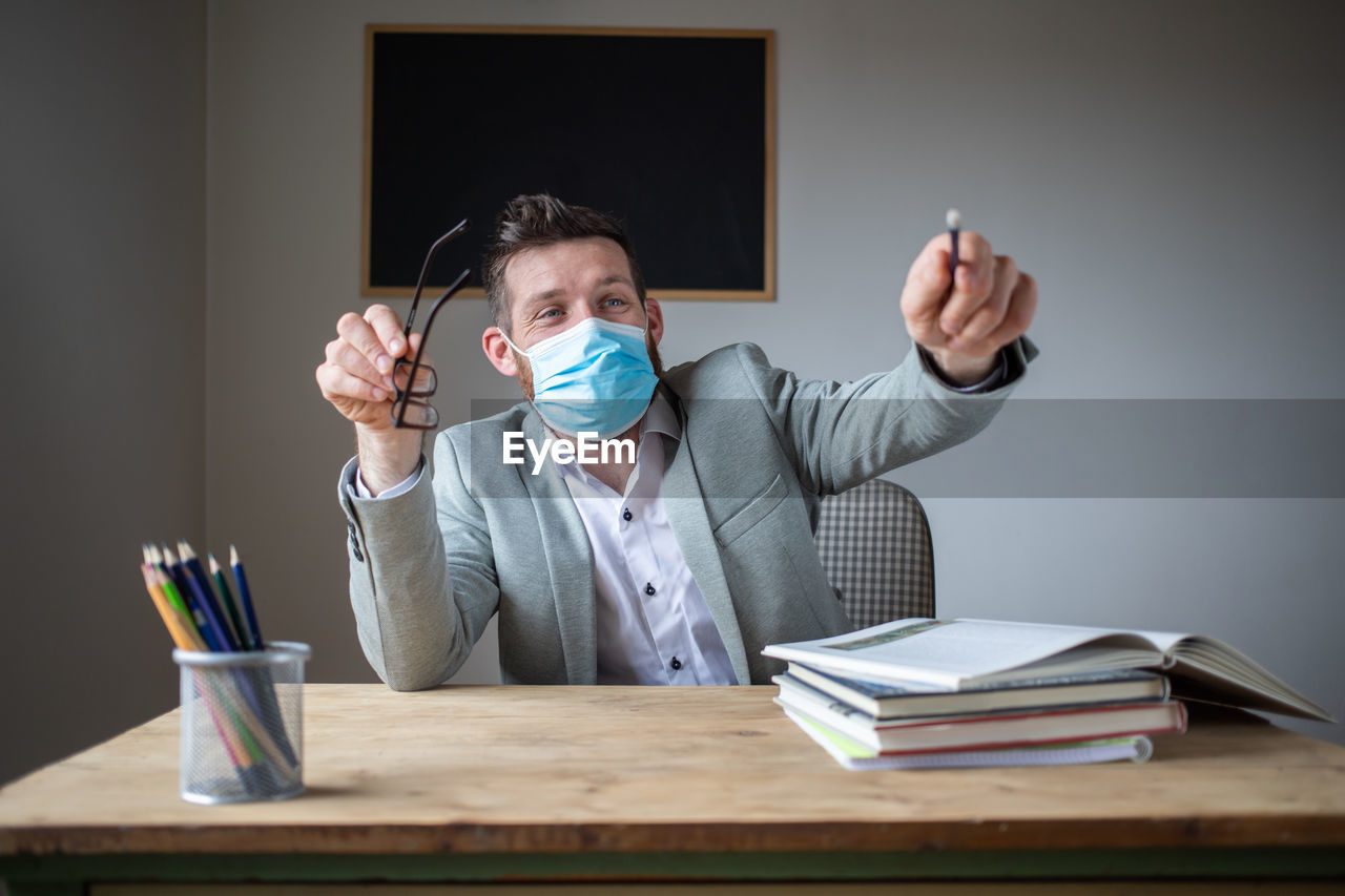 PORTRAIT OF MAN SITTING ON BOOK