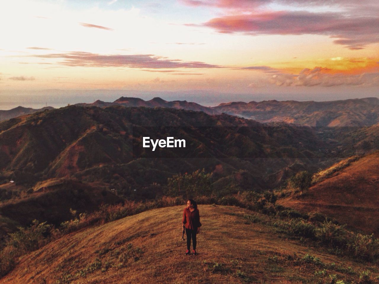 High angle view of woman standing on mountain against sky during sunset