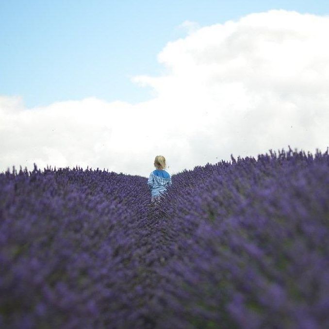 WOMAN STANDING ON FIELD AGAINST CLOUDY SKY