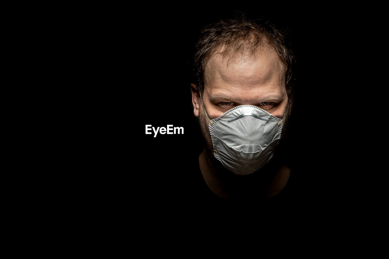 Portrait of a man with mask against black background