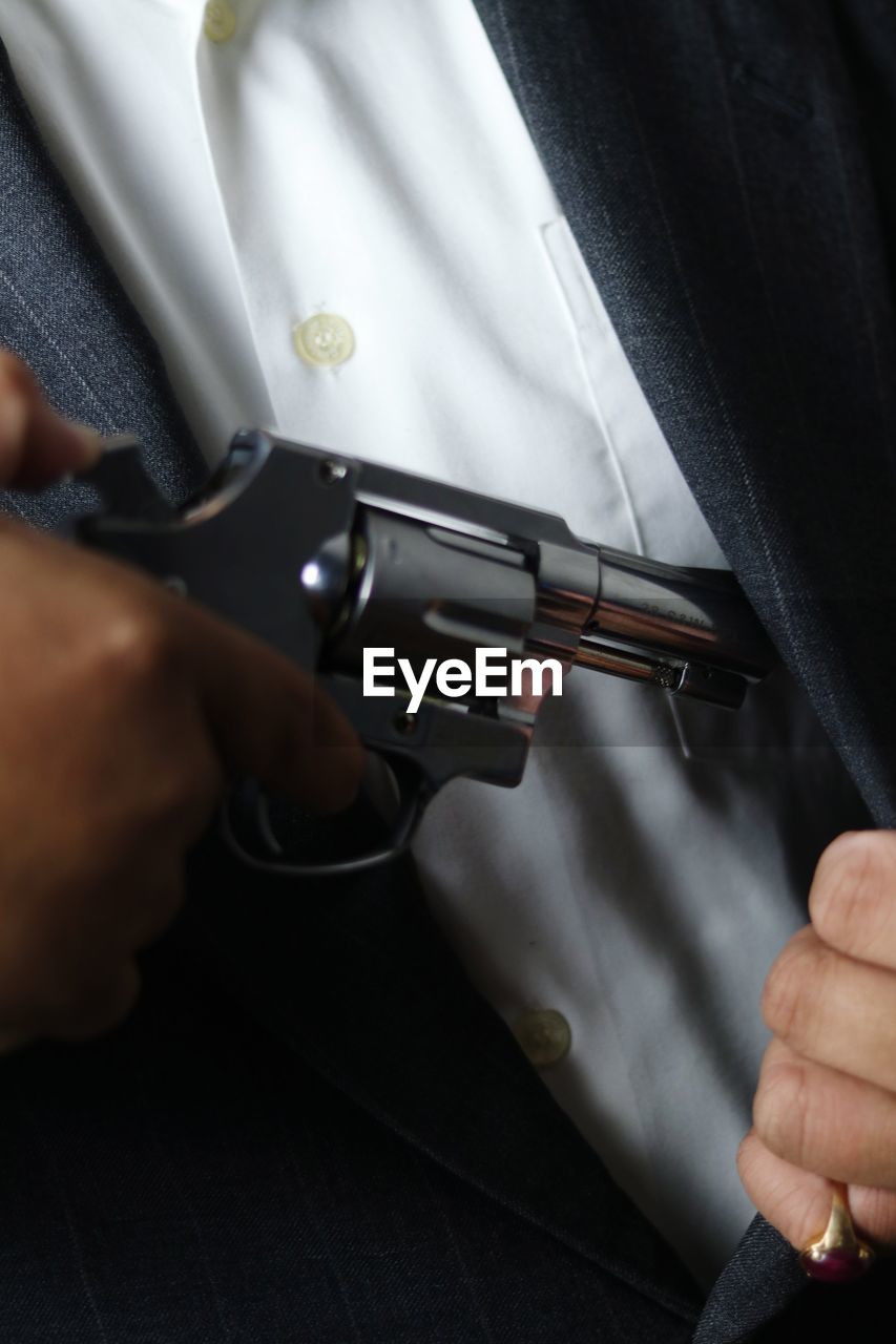 cropped hand of man holding gun
