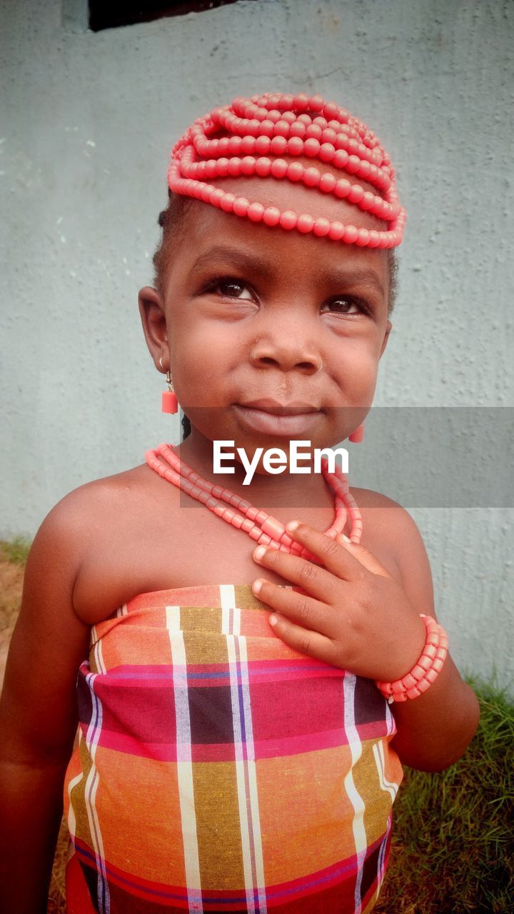 Portrait of young woman standing against wall