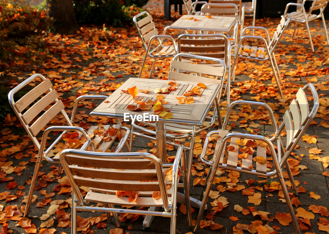 Autumn leaves on chairs and table at sidewalk cafe