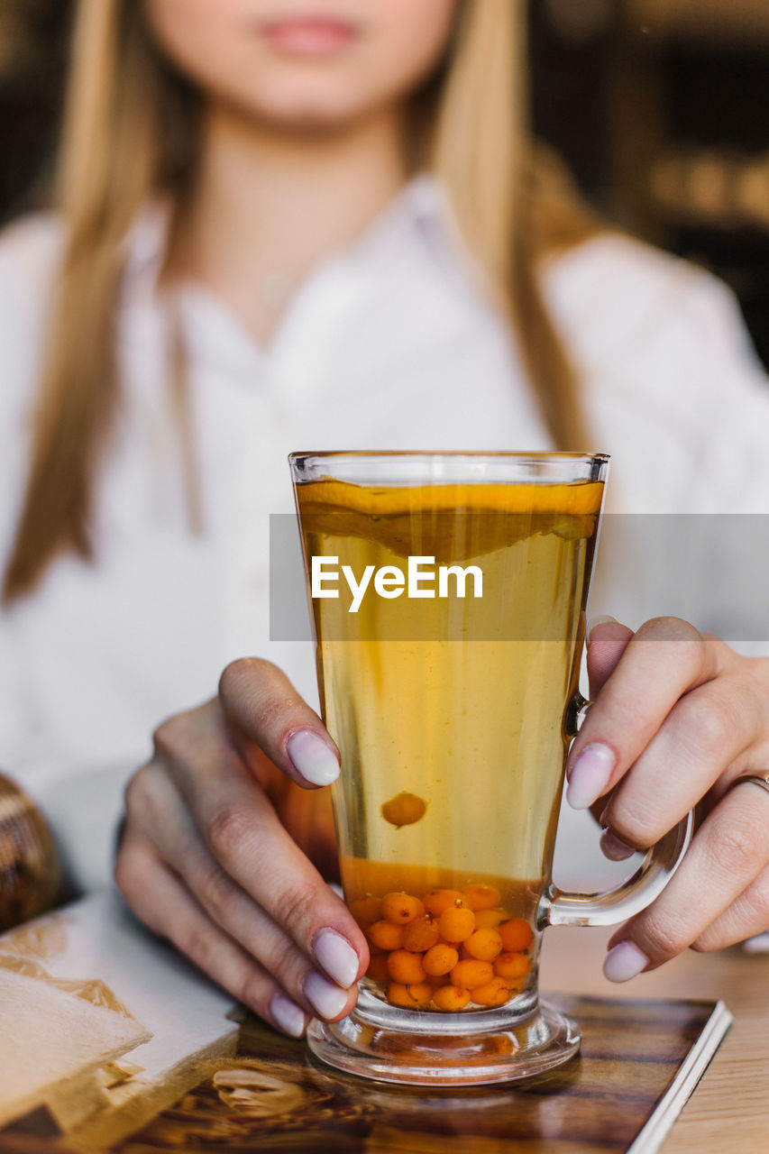 MIDSECTION OF WOMAN HOLDING GLASS OF JUICE