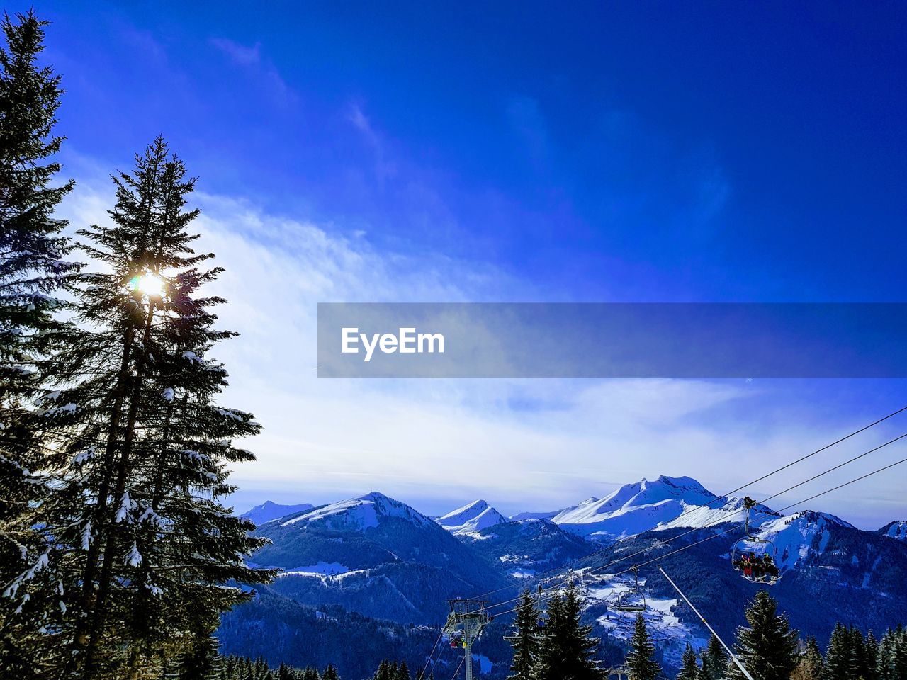 Low angle view of snowcapped mountains against blue sky