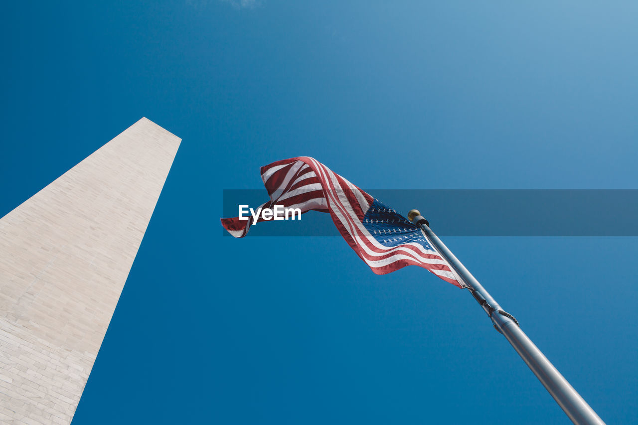 Low angle view of american flag fluttering against clear blue sky
