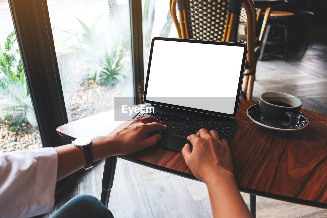 midsection of woman using laptop while sitting on table