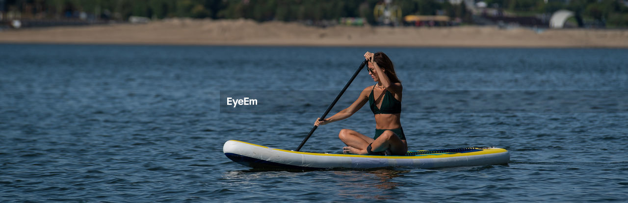 Full length of woman paddleboarding in sea