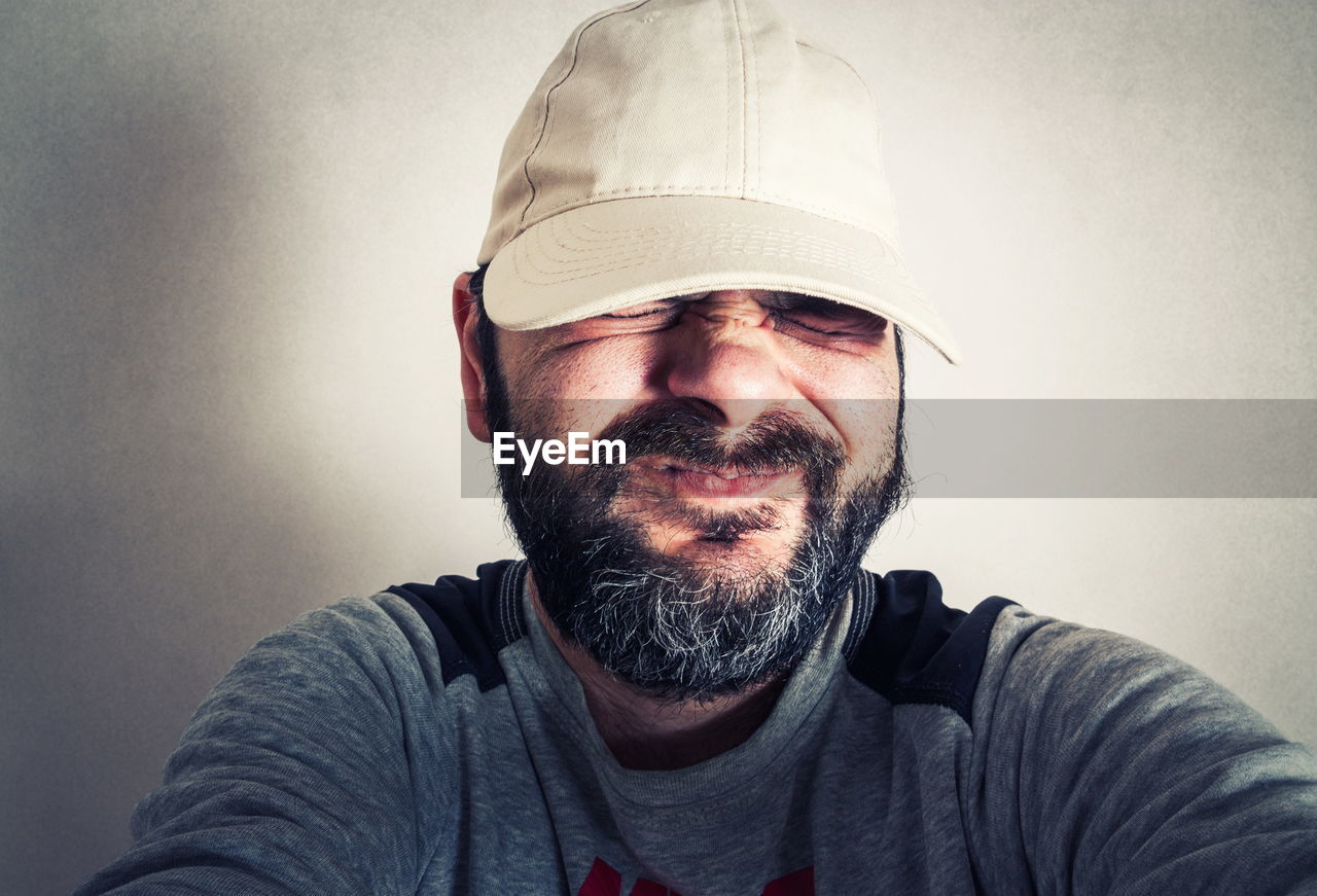 PORTRAIT OF MAN WITH HAT AGAINST WALL