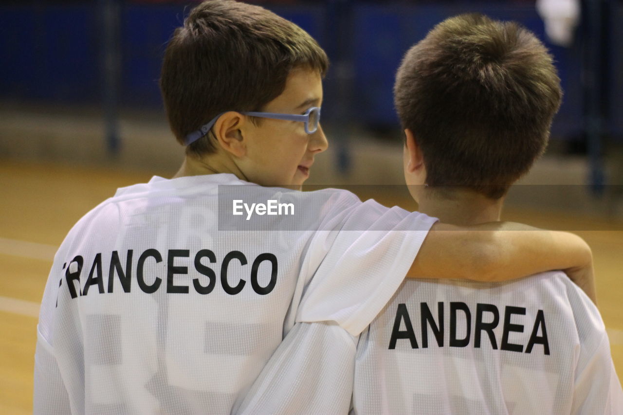 Rear view of siblings with arm around wearing t-shirt with text