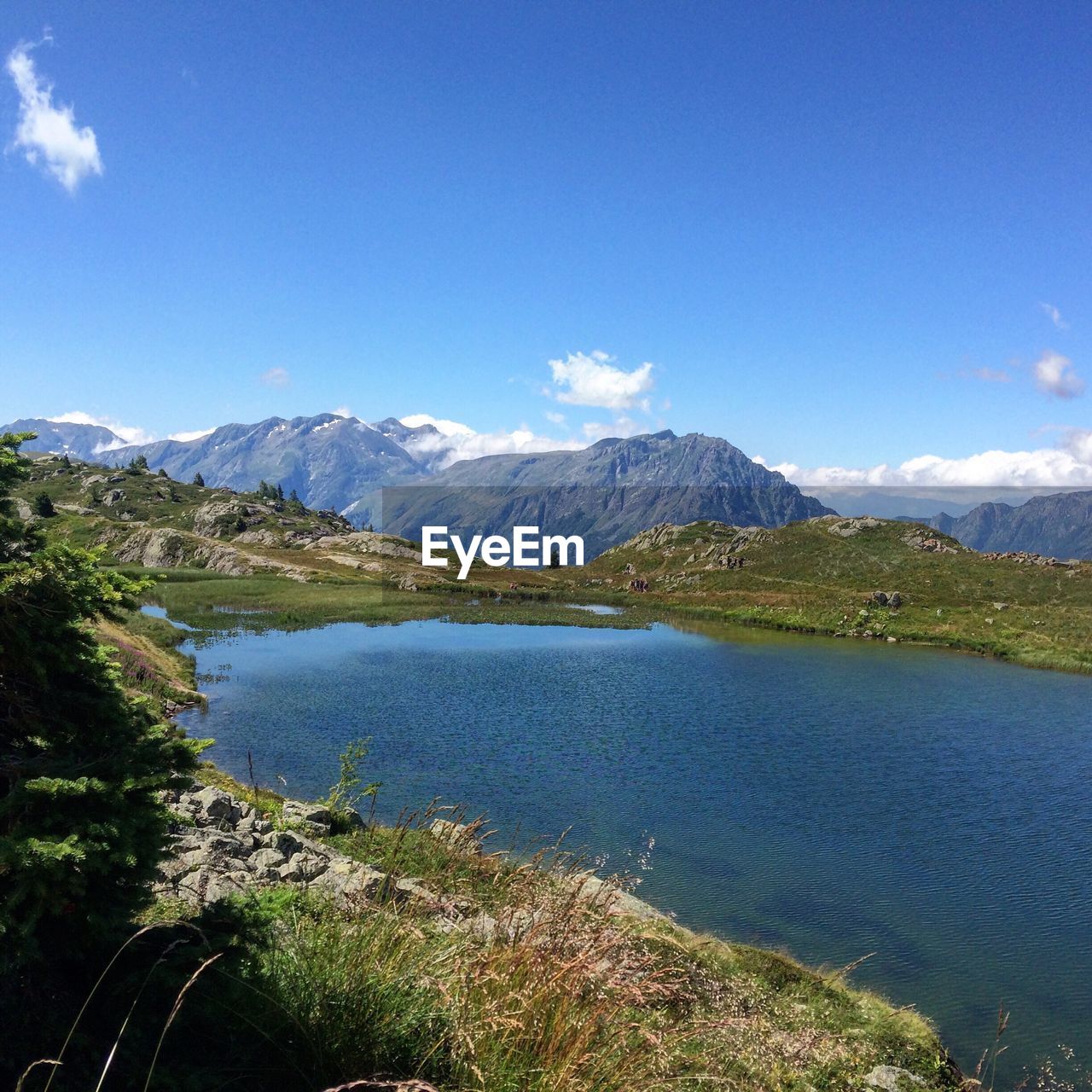 Scenic view of lake and mountains against blue sky at huez