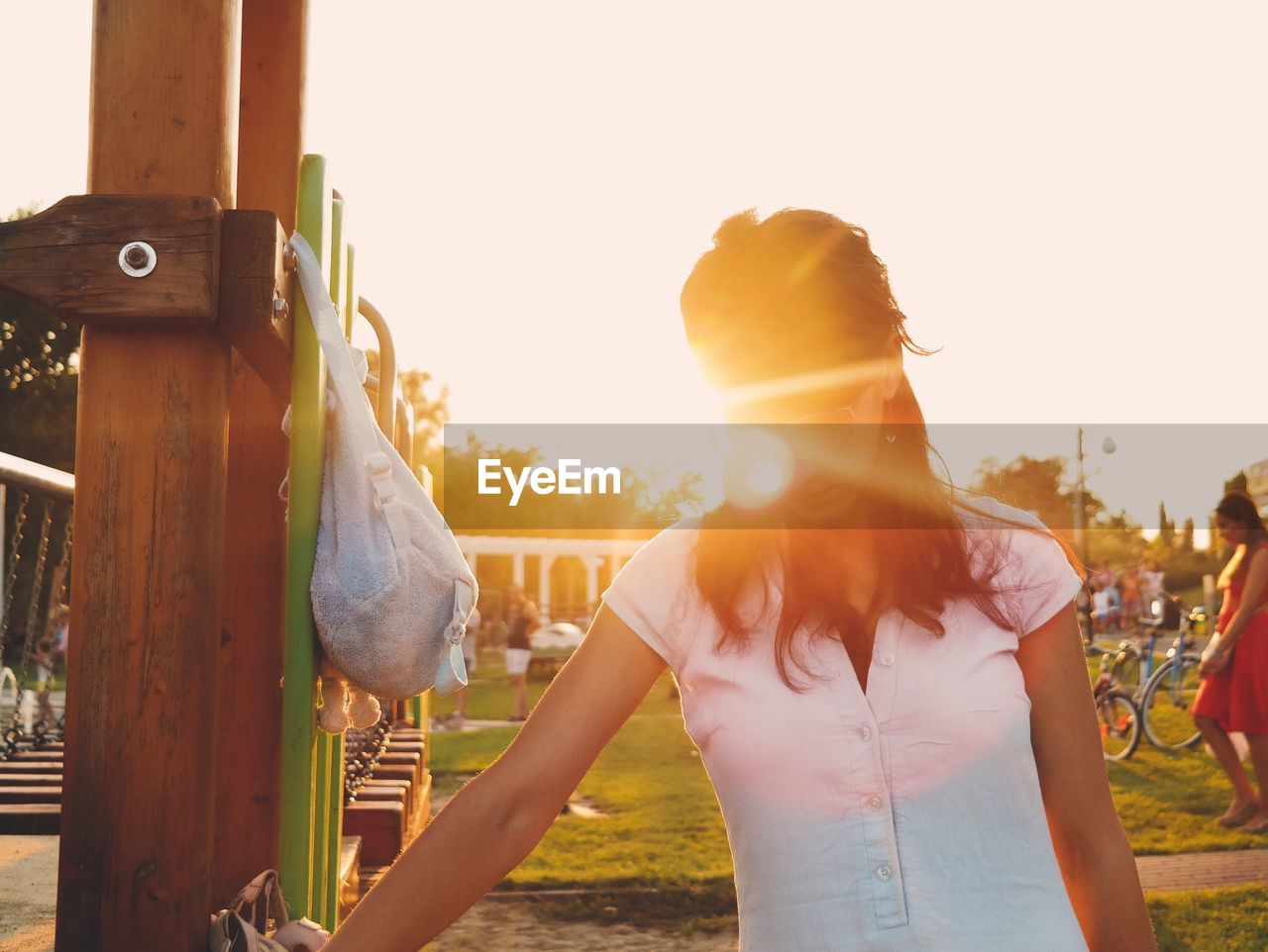 Woman standing in park against sky on sunny day