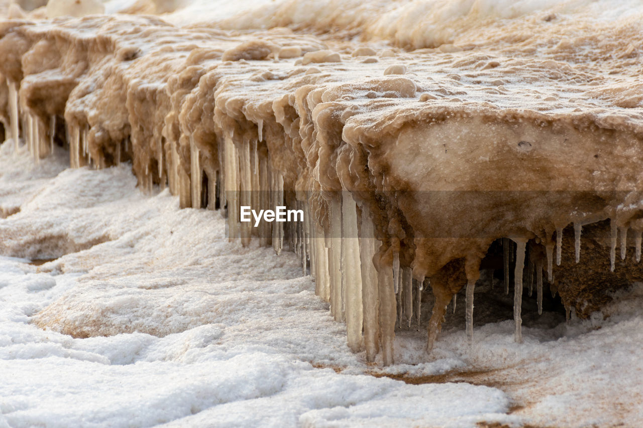 Lying pieces of ice on the seashore, icicles of different sizes, textures of sand in the dunes