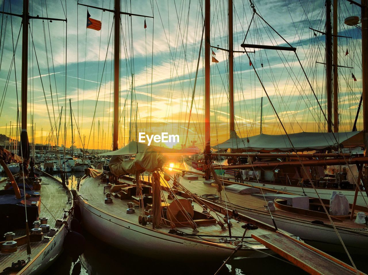 Boats moored at harbor during sunset