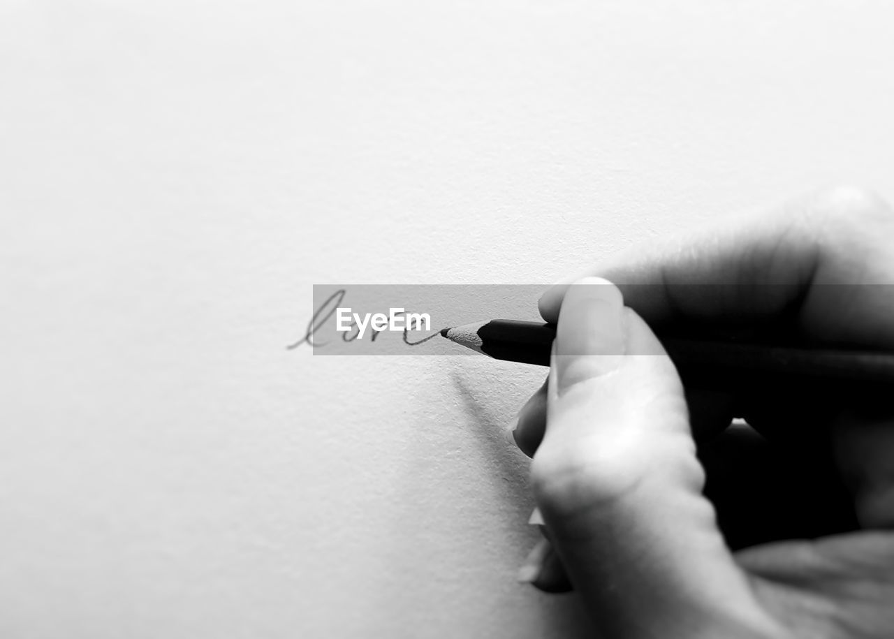 Close-up of hand writing love on paper 