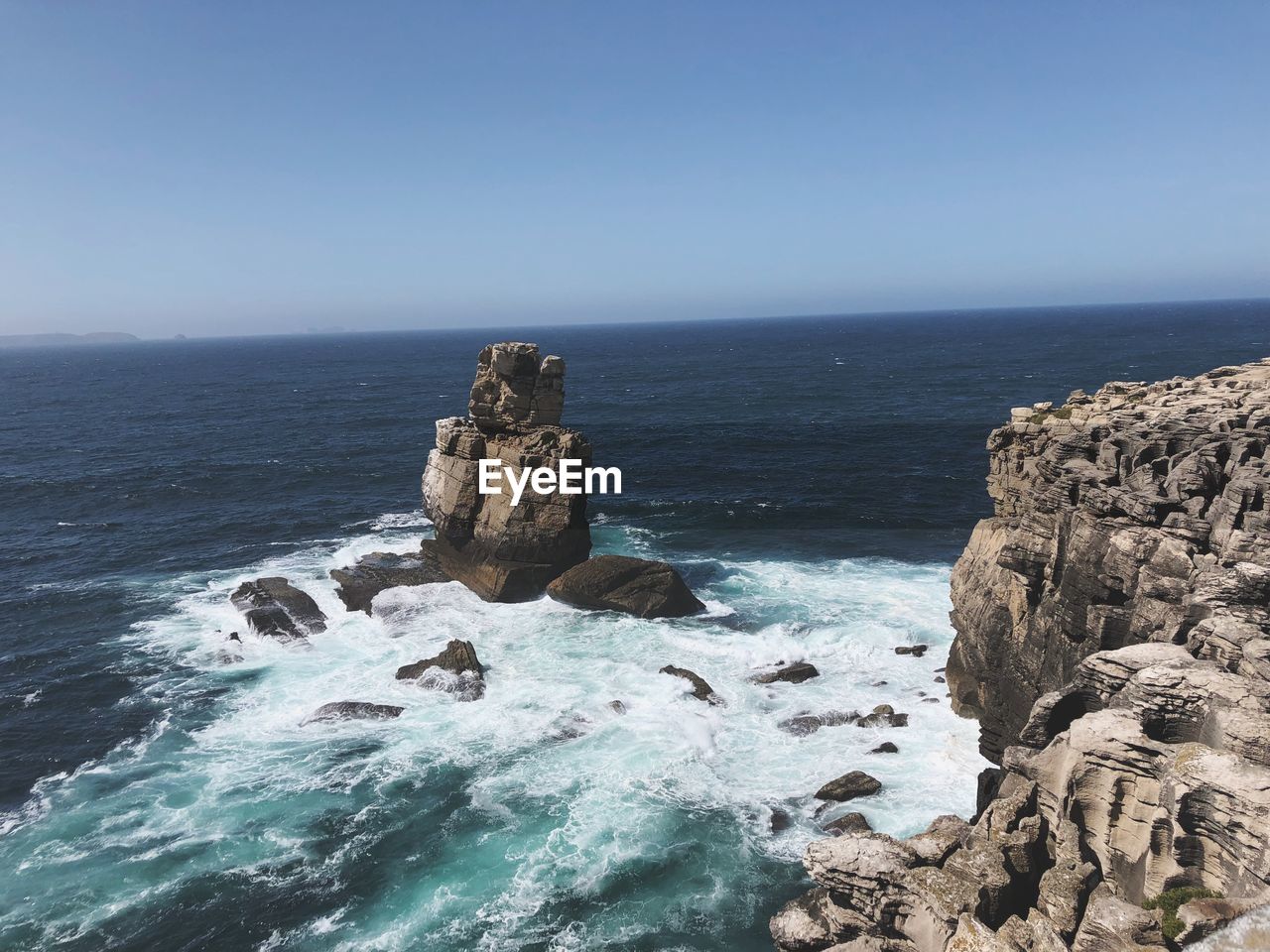 Rocks in sea against clear sky