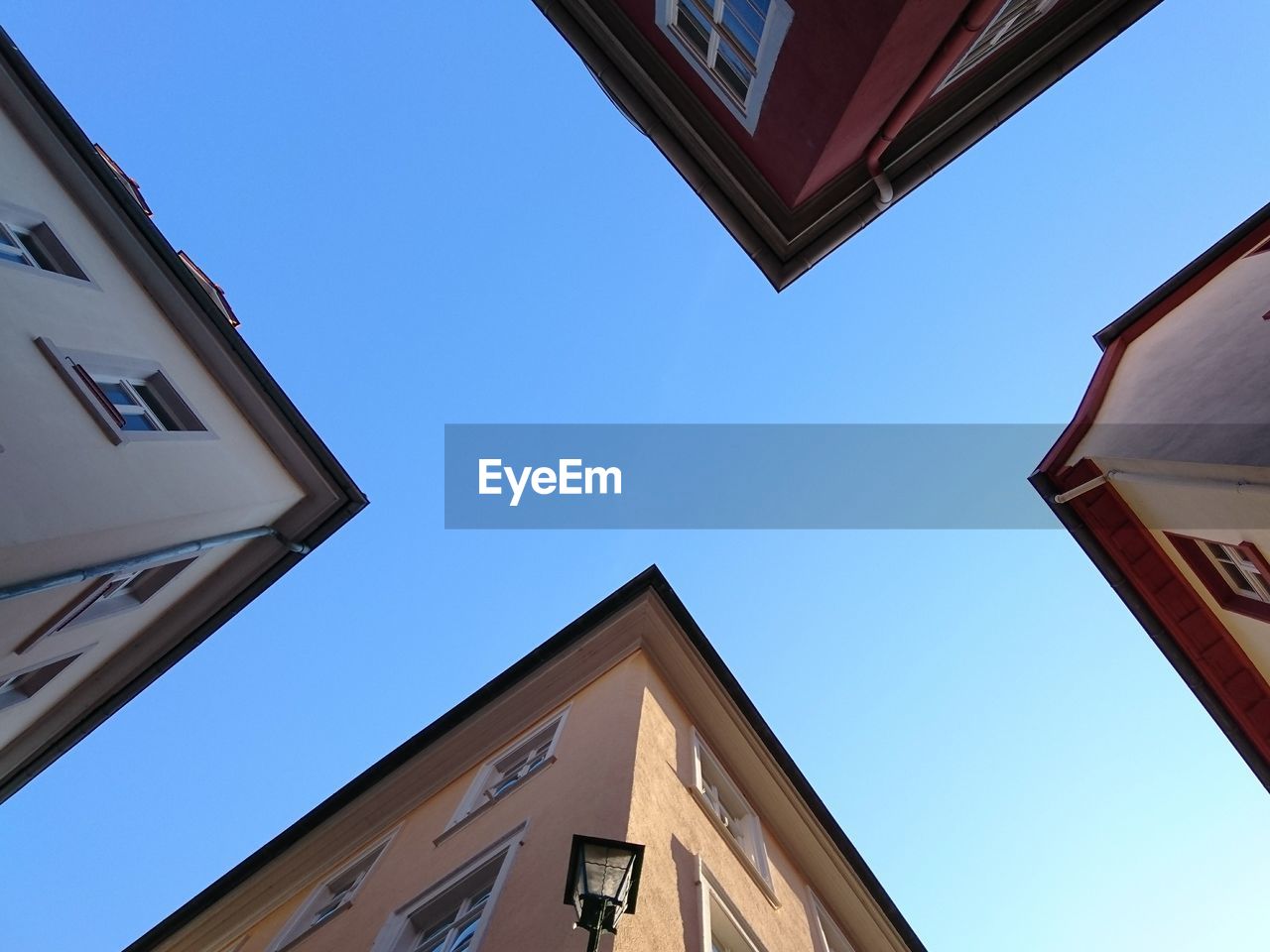 Directly below shot of buildings against clear blue sky