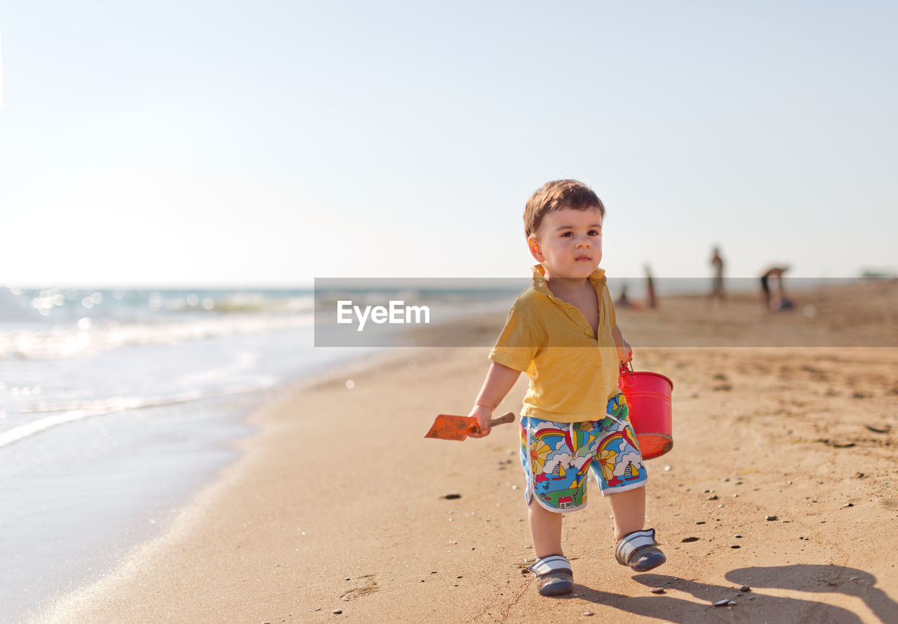 Cute boy carrying bucket at beach