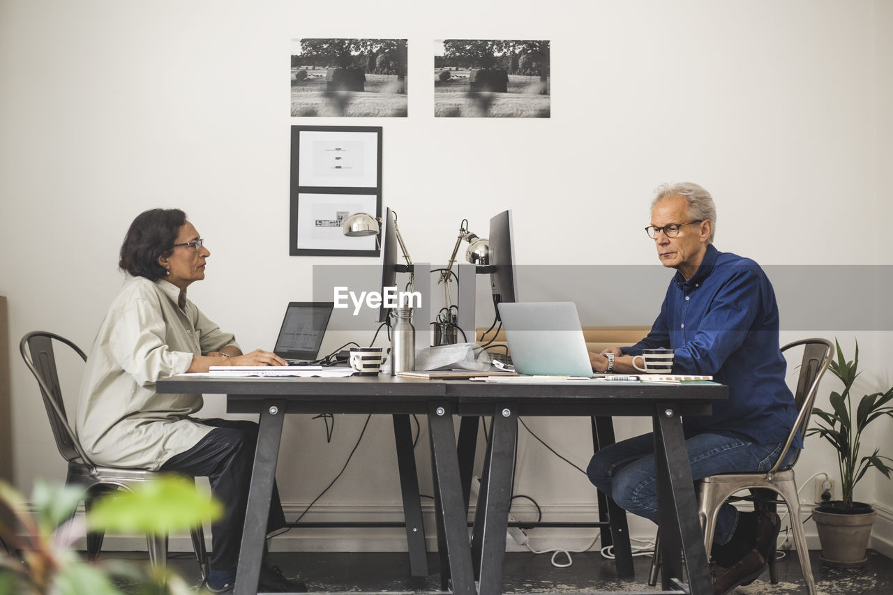 Senior male and female colleagues working on computer in office