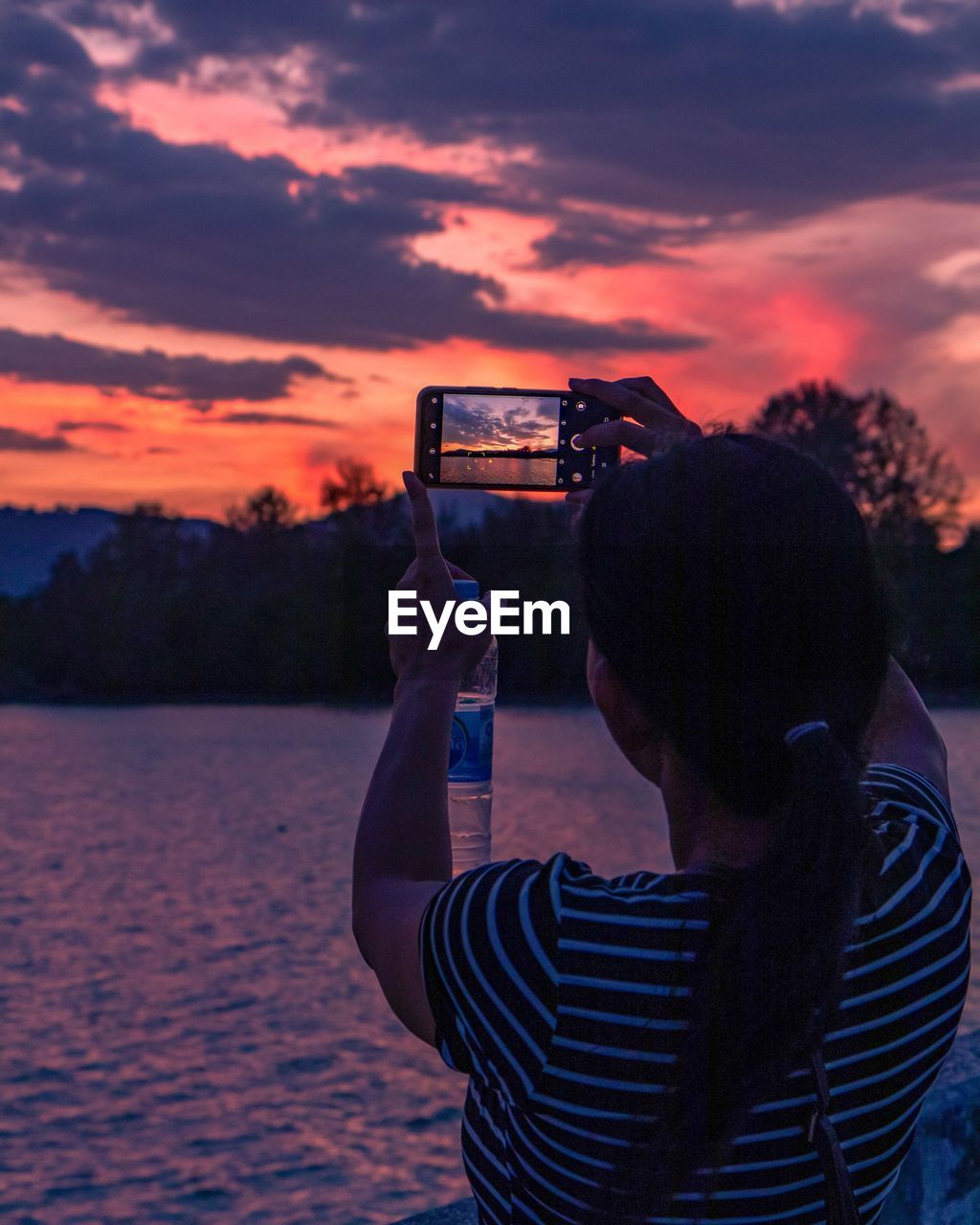 MAN PHOTOGRAPHING WITH MOBILE PHONE AT SUNSET