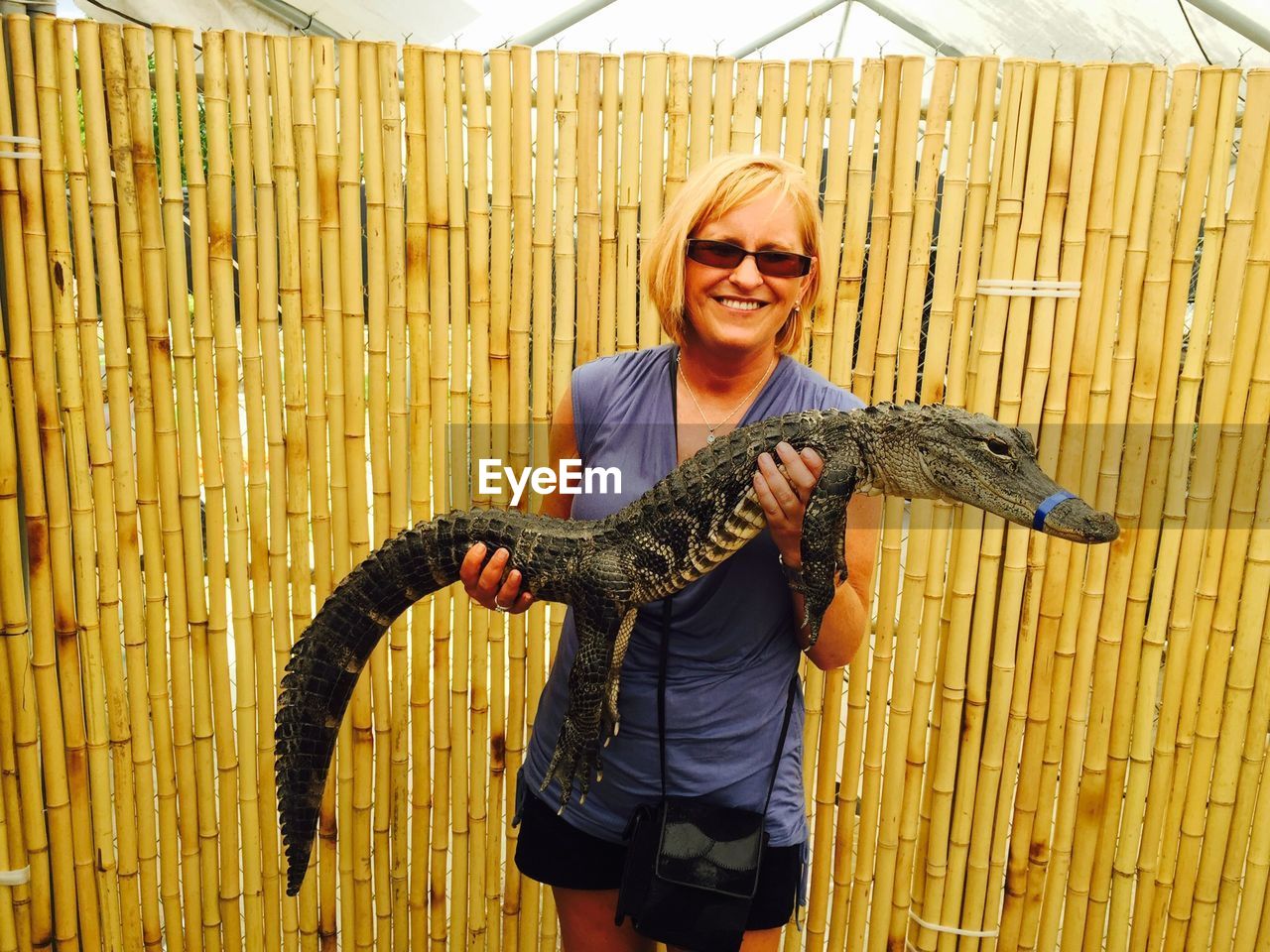 Portrait of smiling mature woman holding crocodile