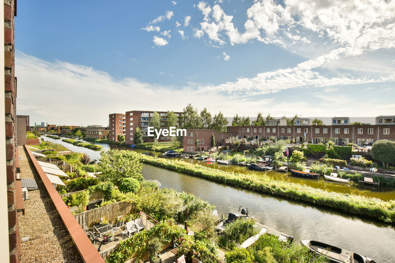 RIVER AMIDST BUILDINGS AGAINST SKY