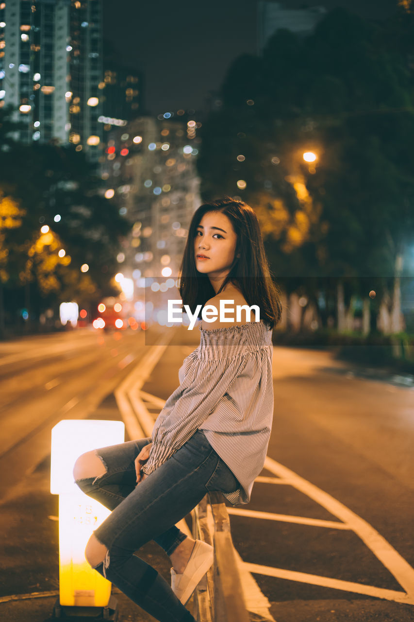 Portrait of young woman on street at night