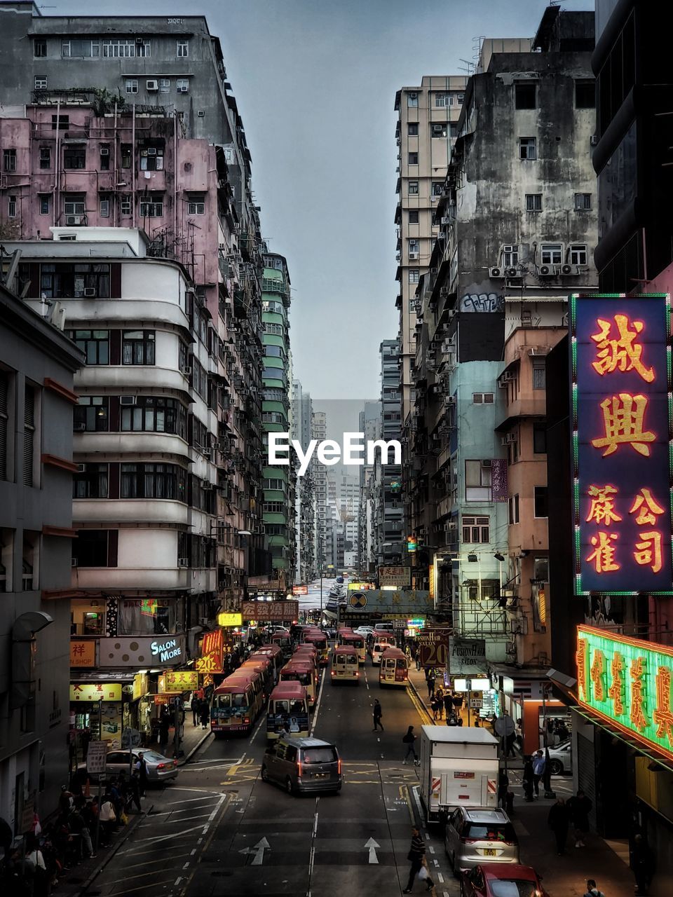 TRAFFIC ON CITY STREET AMIDST BUILDINGS AGAINST SKY