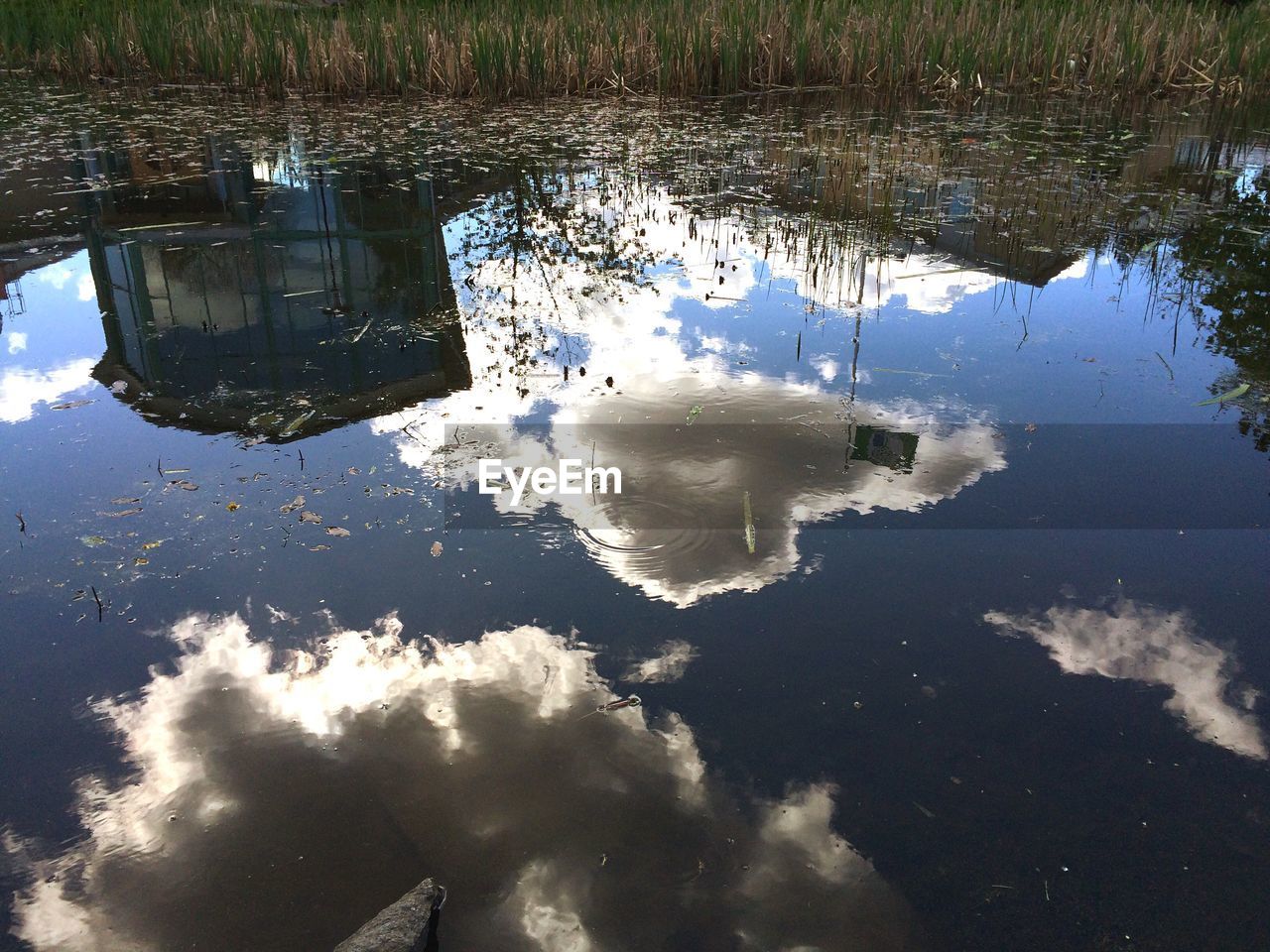 Building and clouds reflecting in pond