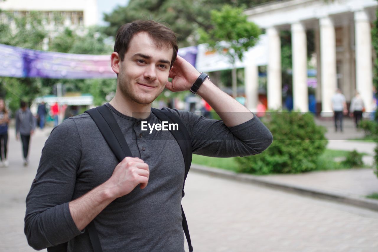 Young man with hand in hair standing in city