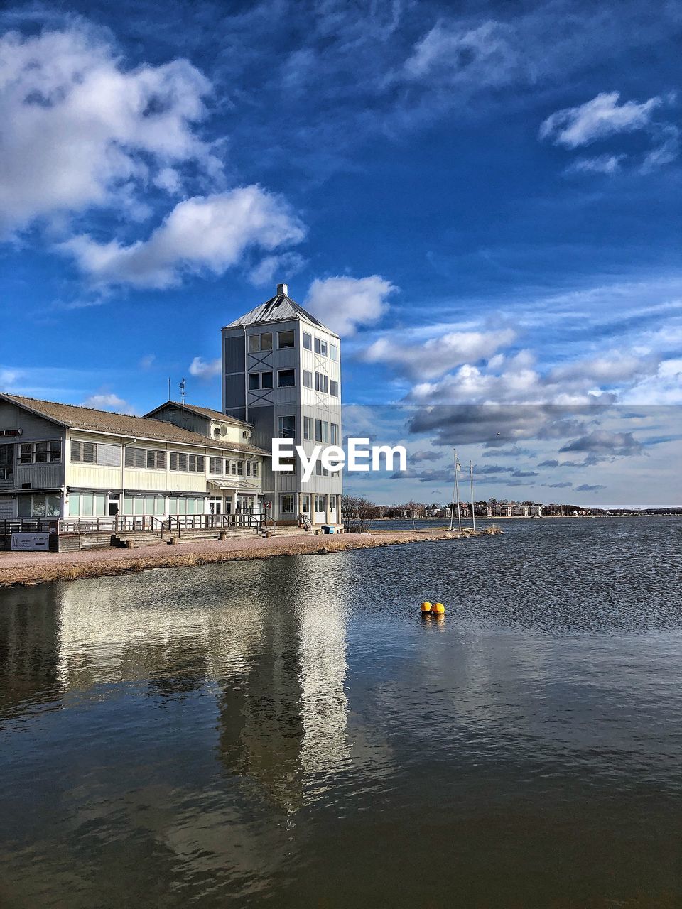 BUILDINGS BY RIVER AGAINST BLUE SKY