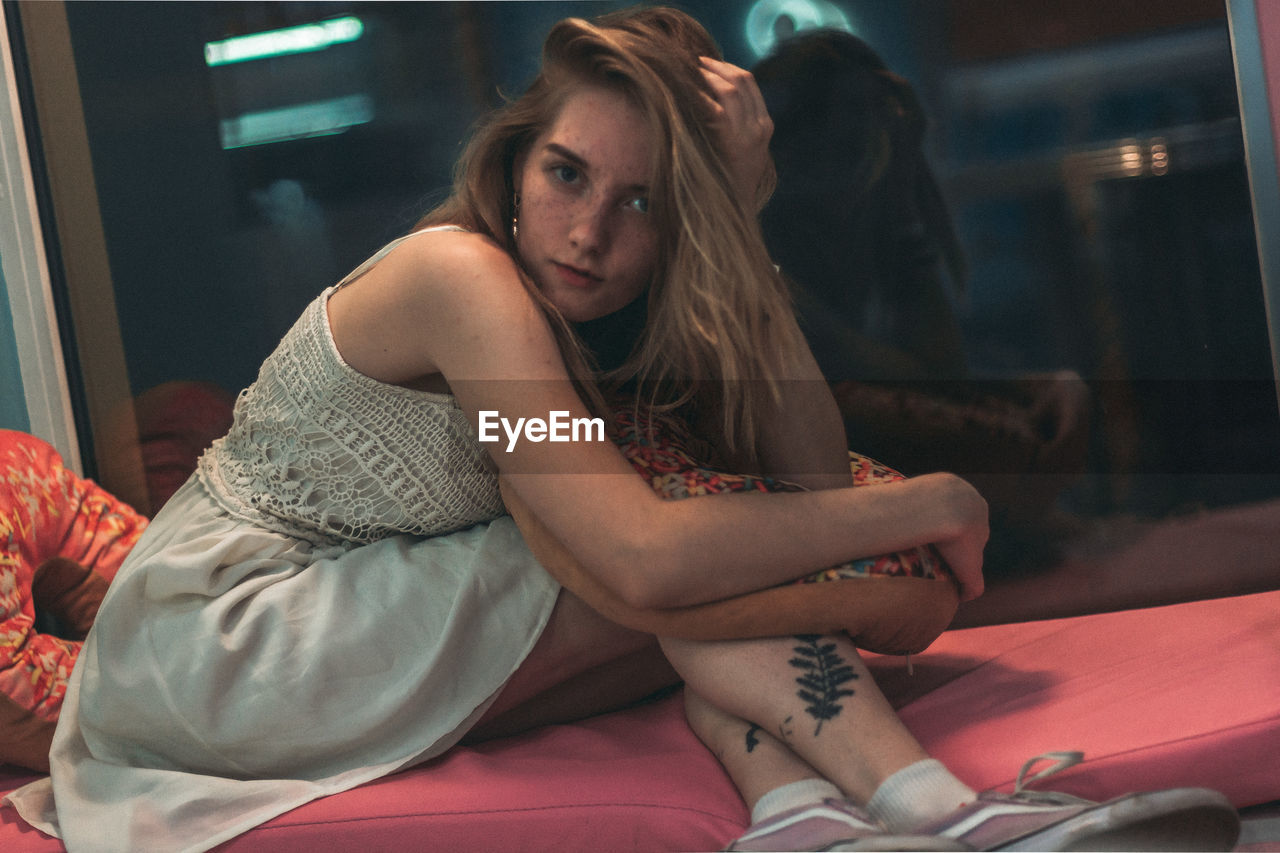 WOMAN SITTING ON BED IN BEDROOM