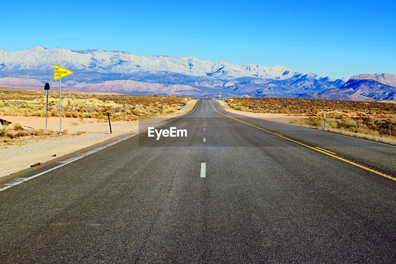 Road leading towards mountains against sky